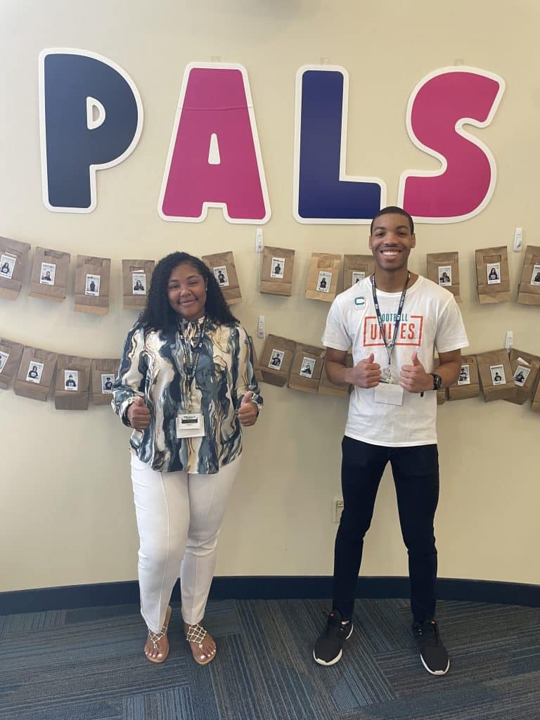 Two NVEEE interns standing in front of the PALS welcome wall