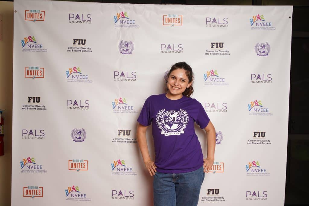 An intern in a PALS shirt at the step-and-repeat