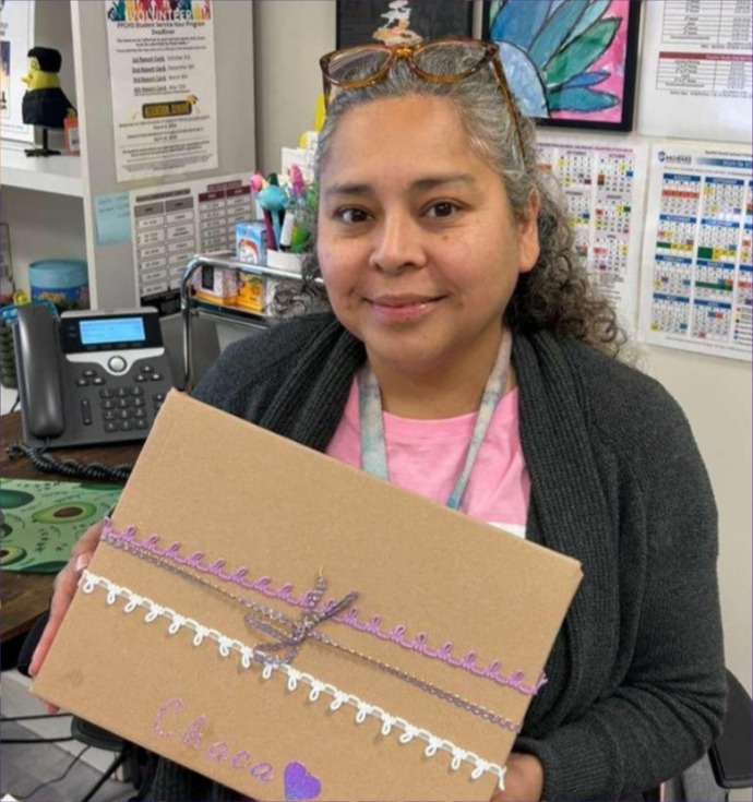 An educator smiles while holding up her wrapped Share the Care kit