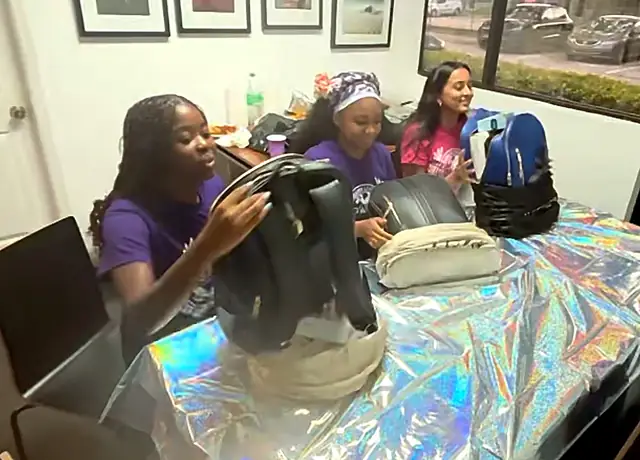 Three graduating ambassadors smiling as they look through their Wellness Kits